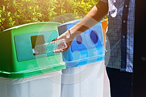 Black hand throwing an empty plastic water bottle in the recycling garbage trash