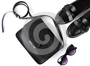 Black handbag, black loafers ,sunglasses on a white background. Flat lay, top view of female fashion accessories.