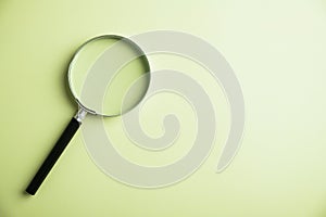 Black handled magnifying glass on a light green background