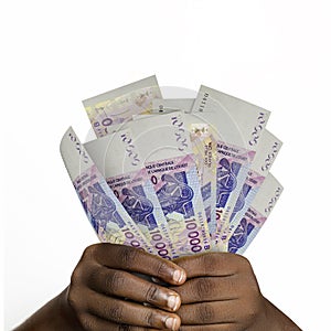 Black hands holding 3D rendered 10000 west African Cfa franc notes. closeup of Hands holding Cfa franc currency notes