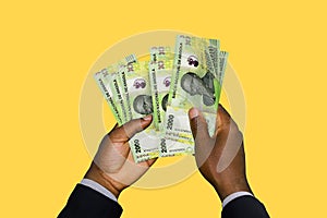 Black Hands in suit holding 3D rendered Angolan Kwanza notes