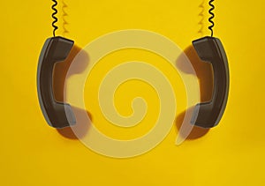 Black handsets on yellow background.