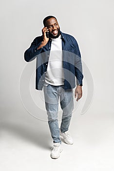 Black happy man talking on the phone over isolated grey background