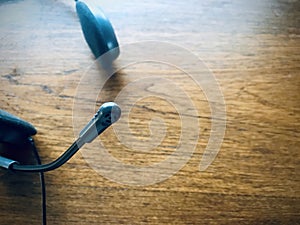 A black headset on wooden background. Select focus on the mic. Cool tone.