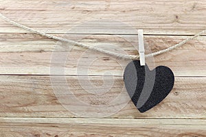 Black Heart hung on hemp rope isolated on wooden background.
