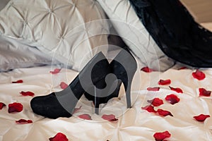 Black heels on bed with roses