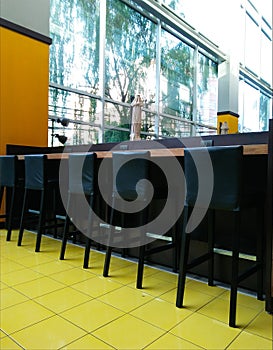 Black high chairs and counter on yellow floor.