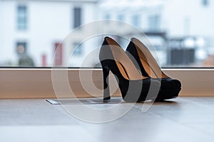 Black high heel pumps in front of a window and on a light floor