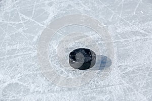 Black hockey puck on ice rink