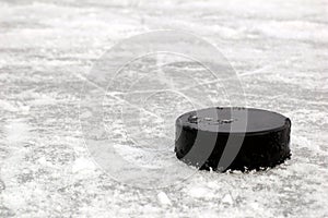 Black hockey puck on ice rink