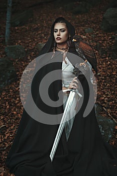 Black hooded woman with sword and hawk