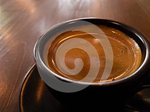 Black hot coffee mug on wooden floor Close-up photo