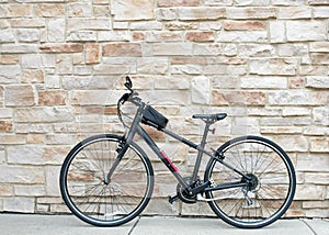 Black Hybrid Bicycle Against Tan Flagstone Wall