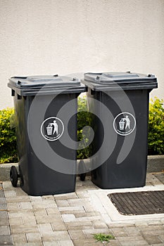 Black indoor waste containers for recycling and garbage. A lot of closed and recycle receptacles trash bin outside.