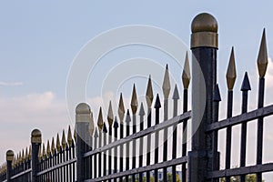 black iron fence with golden decorative elements in linear perspective with selective focus