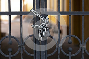 Black iron gate with rust closed on padlock with chains