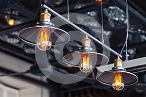 Black iron loft chandeliers with edison lamps on a black background, bokeh. Concept of modern interior design of restaurant, cafe