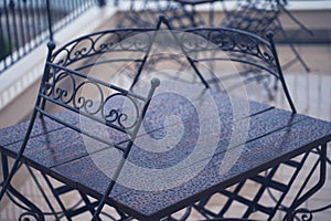 Black iron metal chairs near table on rainy outdoor terrace