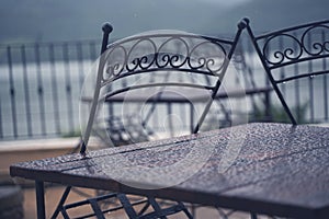 Black iron metal chairs near table on rainy outdoor terrace