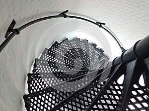 Black iron metal spiral staircase and white wall in lighthouse