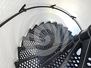 Black iron metal spiral staircase and white wall in lighthouse
