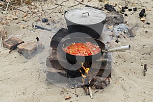 black iron pan with roasting vegetables and big cooking pot with soup