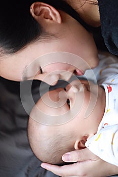 Black isolated background baby and mother mom face-to-face look at each other smile grin on face happy family maternal love