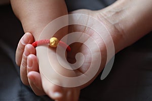 Black isolated background baby put little foot on his mother palm hand maternal love family concept golden bracelet means happines