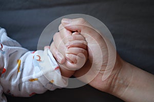 Black isolated background baby put little hand in his mother palm maternal love family concept hand-in-hand