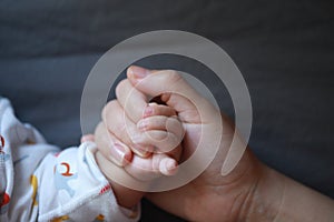 Black isolated background baby put little hand in his mother palm maternal love family concept hand-in-hand