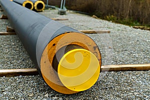 Black isolated heating pipe with yellow plastic plug lie on a construction site