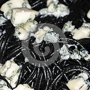 Black Italian spaghetti  pasta with blue cheese with mold and olive oil  macro picture. Home cooking.