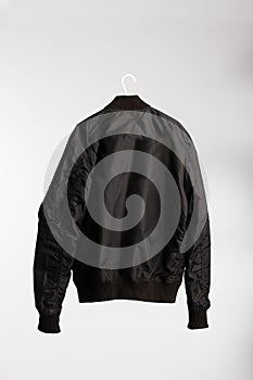 Black jacket on cloth hanger with white wall in the background