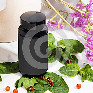 Black jar with red oil capsules with fresh mint in bathroom