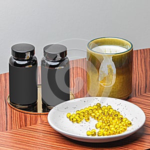 Black jars on wooden table with plate of yellow natural oil capsules and green candle