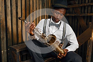 Black jazz musician sitting with saxophone