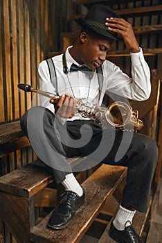 Black jazz musician sitting with saxophone