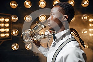 Black jazz performer poses with saxophone on stage