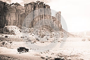 A black Jeep Wrangler alone in a southwest desert landscape will large cliffs in the distance
