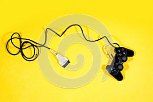 Black joystick, game controller with broken cable isolated on yellow background