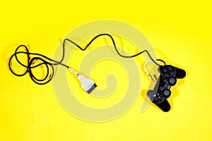Black joystick, game controller with broken cable isolated on yellow background.