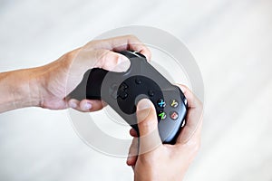 Black joystick in hands isolated on white background. The guy is playing on the console. Computer gaming technology play competiti