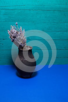 black jug with lavender flowers on a blue background