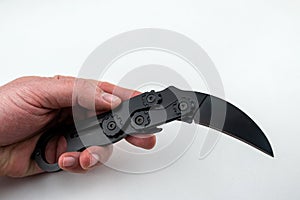 black karambit knife in hand on isolated white background
