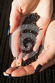 Black keratin granules in a woman`s hands are used to encapsulate strands of hair