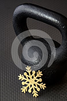 Black kettlebell on a black gym floor with a gold snowflake