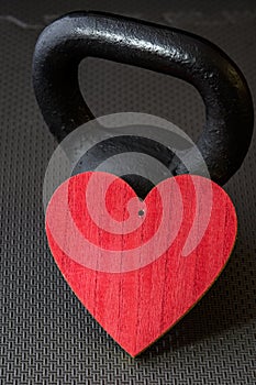 Black kettlebell on a black gym floor with large red heart