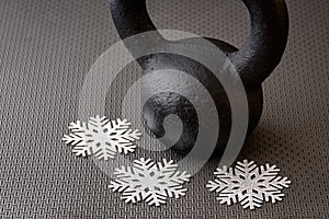 Black kettlebell on a black gym floor with three silver snowflakes