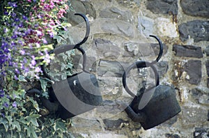 Black kettles hanging on stone wall