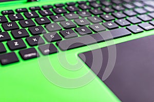 black keyboard on a green laptop. keys with letters and numbers. Detail of a laptop computer. Image detail to describe IT tools,